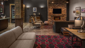 Lobby lounge of Four Points by Sheraton Juneau hotel with brick fireplace, distressed wood decor, beige & brown couches & table.