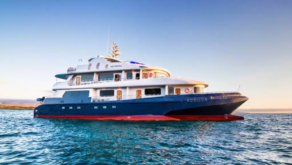 The exterior of the Galapagos Horizon trimaran ship during sunset as it sits at anchor