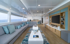 Lounge area with chairs and pillows lining large window viewing the ocean aboard Galapagos small ship Sea Star Journey