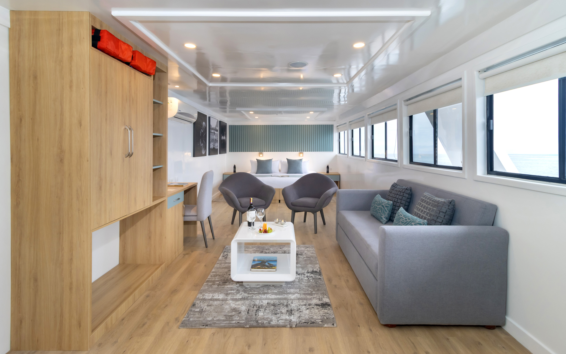 Sea Star Suite aboard Galapagos Sea Star with small grey couch a small seating area, a large double bed and a coffee table