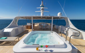 Sundeck chaise loungers with beige and blue pillows plus central hot tub aboard Sea Star Journey Galapagos small yacht.