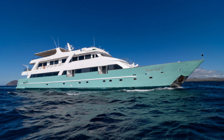 Exterior of the Galapagos SeaStar small ship with green hull and white exterior cruising through the open ocean