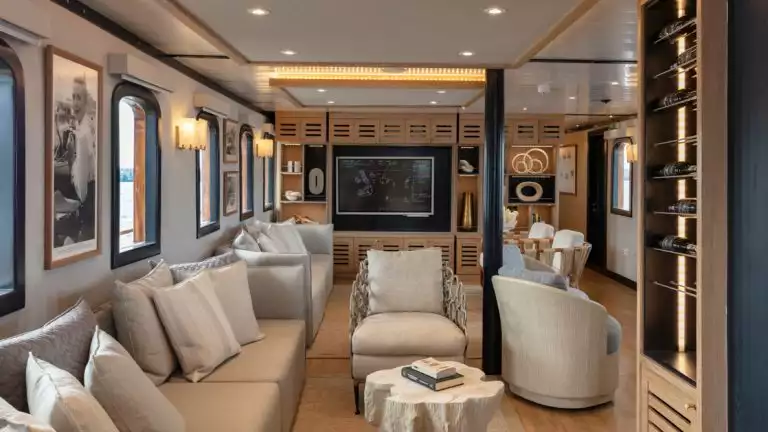 Two beige couches with multicolored pillows beneath a bank of windows arranged in two comfortable conversational spaces