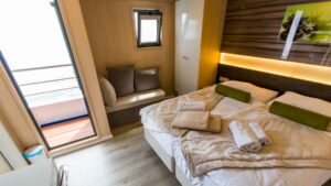 Infinity stateroom with double bed, seating, nightstand and door out to the balcony.