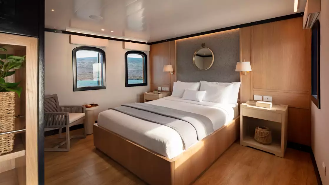Historic wooden cabin Grace Kelly suite with white sheets flanked by two bedside tables with two windows looking outside.