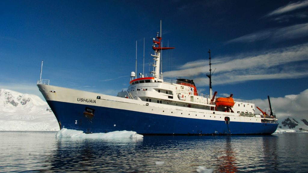 Ushuaia Antarctic ship in ocean with ice bergs nearby and Antarctica behind the ship operated by Antarpply expeditions