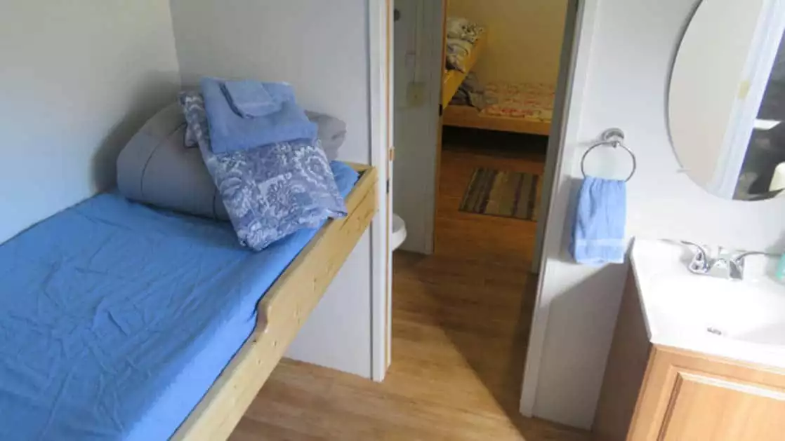 Standard cabin aboard Ursus with twin bed, sink, and door way.