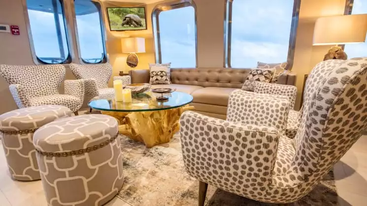 origin, theory & evolve galapagos luxury yacht main lounge with comfortable chairs and large windows looking out to sea