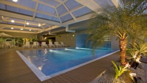 The indoor pool at Casa Andina Private Collection Miraflores, with lounge chairs and a palm tree, is a respite for guests traveling in Peru.