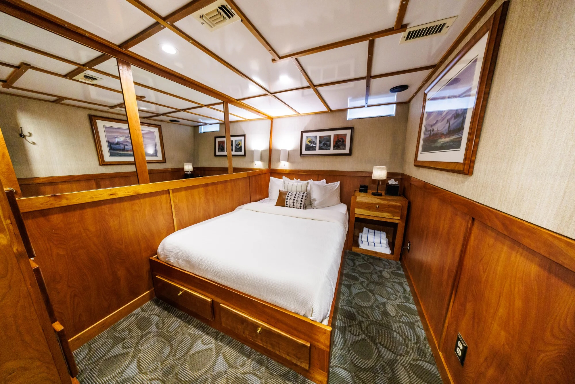 Safari Quest Alaska small ship Navigator stateroom with a large bed, wall mirror and end table