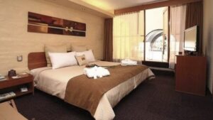 A room with a king-sized bed, doors to a private balcony, artwork, and drapes at Sonesta Posada Del Inca Arequipa, a luxury boutique hotel