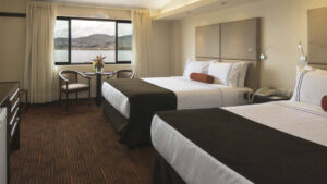 A room with two queen-sized beds and windows offering a view of Lake Titicaca at Sonesta Posada del Inca, a traditional retreat in the andes