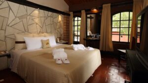 The suite features a stone-tiled wall, king-sized bed, and large windows at Sonesta Posadas Del Inca in Peru's Sacred Valley, a boutique hotel near Machu Picchu.