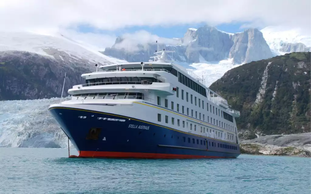The Stella Australis in Chilean Patagonia seen here near a glacier releasing ice into the see with the dramatic Patagonian mountains