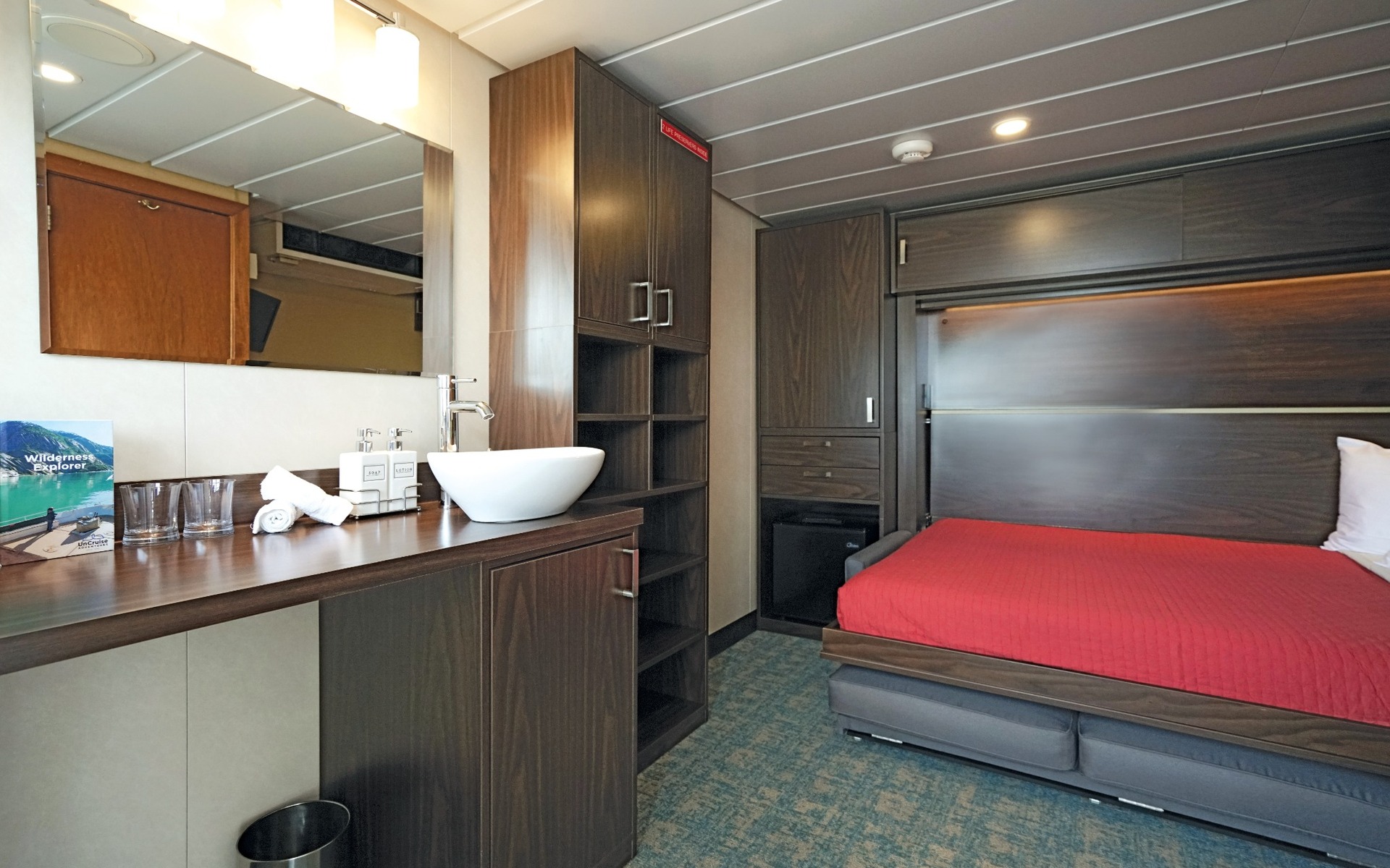 Admiral cabin with a wallbed, desk and sink aboard Wilderness Explorer.