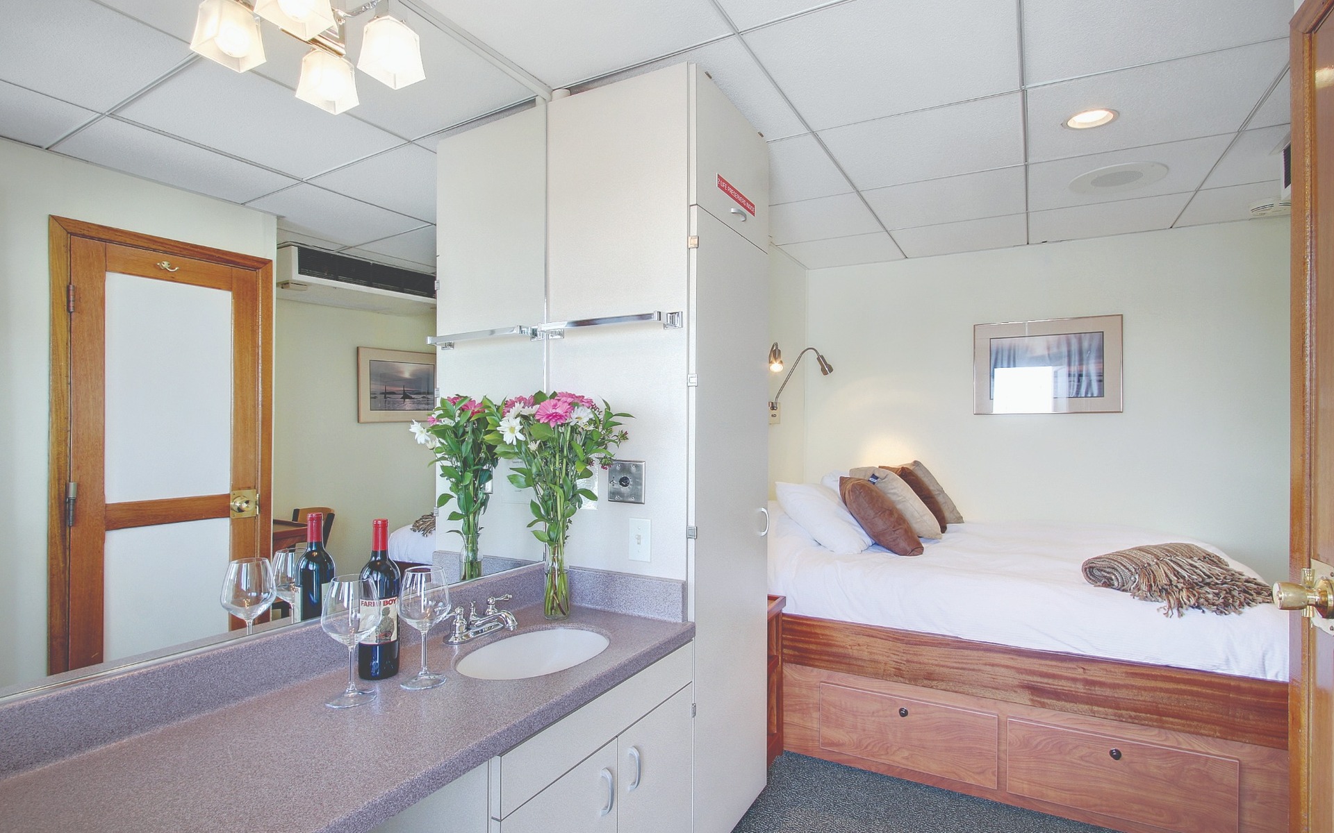 Navigator cabin with white linens on a queen bed, sink and cabinet aboard Wilderness Explorer.