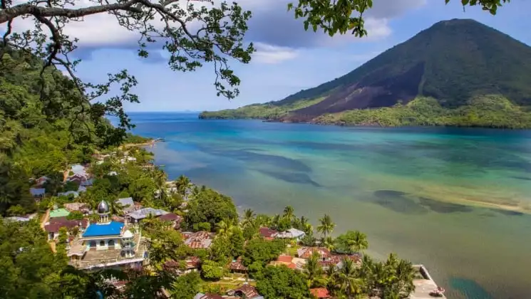 A tropical view of the ocean and red-tiled houses nestled on the trees in the Banda Islands, Indonesia