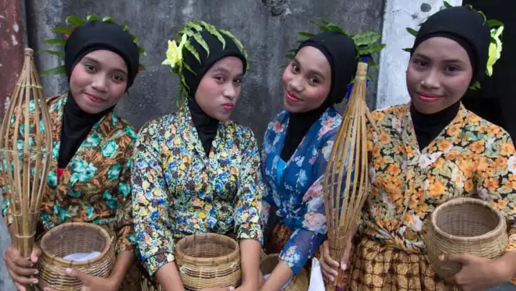 Women dressed in traditional clothing hold spice baskets in indonesia