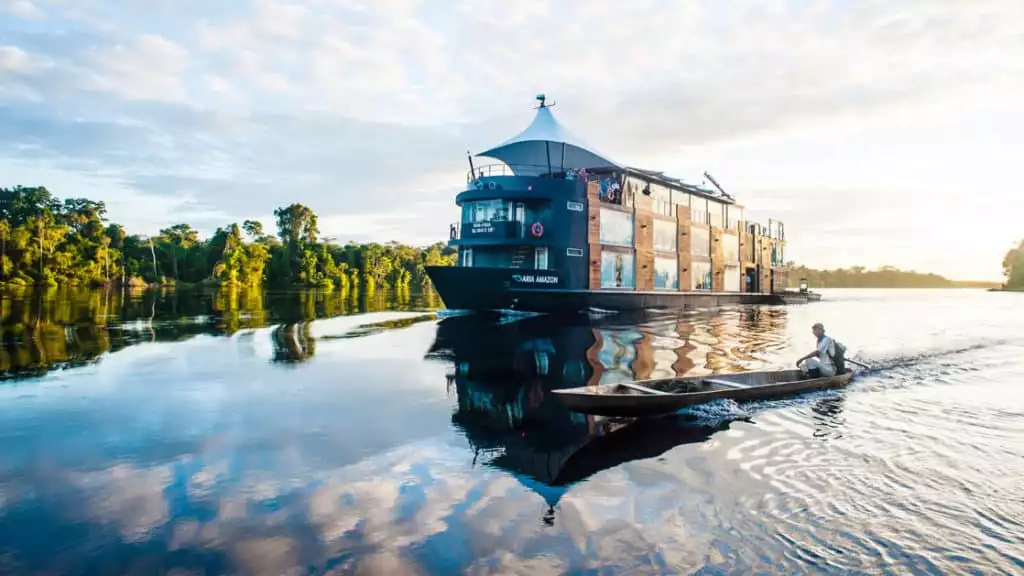 aria small amazon ship cruises down the river on a calm sunny day with the jungle behind it