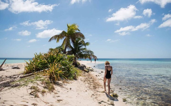 A woman traveler walking along a beach down a point in Belize.