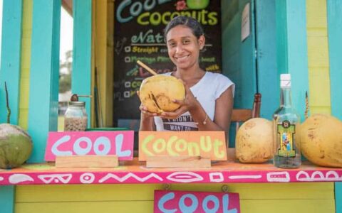 A Belizian shopkeeper selling coconut water with a smile.