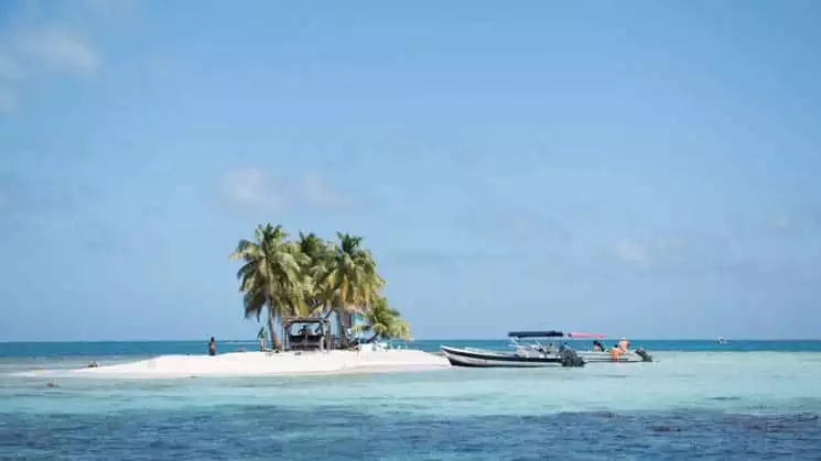 A beach island with palm trees and turquoise water in Belize.