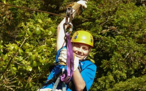 a teen with a yellow helmet ziplining in the jungle canopy on the panama family adventure land tour