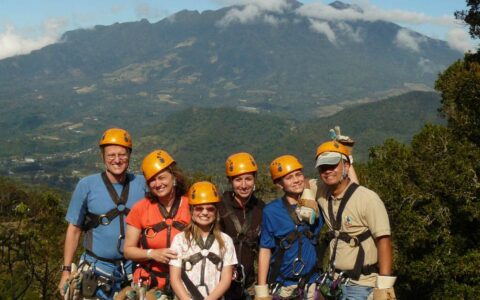 group of adventure travelers with harnesses and orange helmets with mountains in the background on the panama family adventure land tour