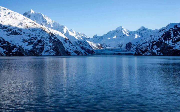 John Hopkins Glacier in Alaska with glacier front and large mountains with sun just on the tips.