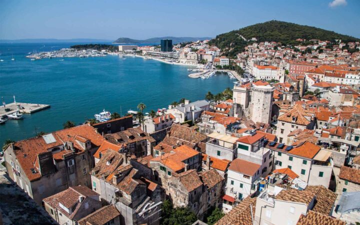 White buildings with red tile roofs on the shore of a Mediterranean harbor