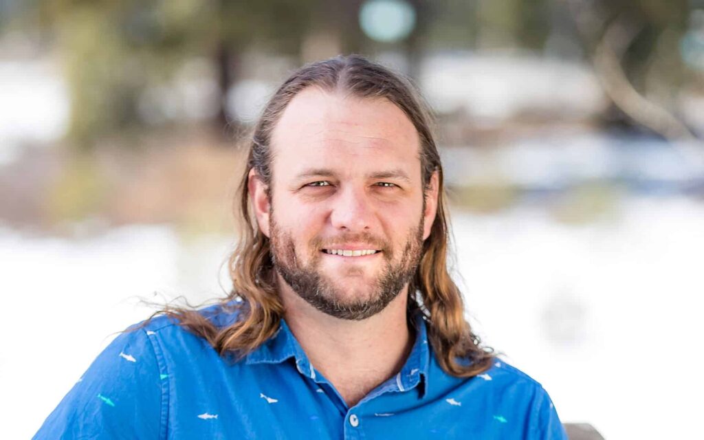 adventuresmith explorations adventure specialist andrew browning wearing a blue shirt smiling with a snowy background