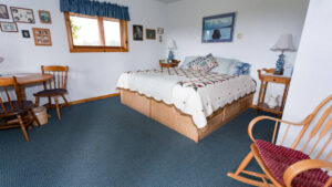 Annie Mae Lodge room with a queen bed, rocking chair and table and chairs.