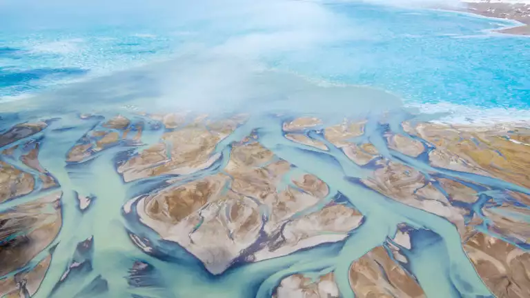 Cunningham Inlet in the Arctic in early July with multiple tributaries of water flowing through the tundra. Seen from above.