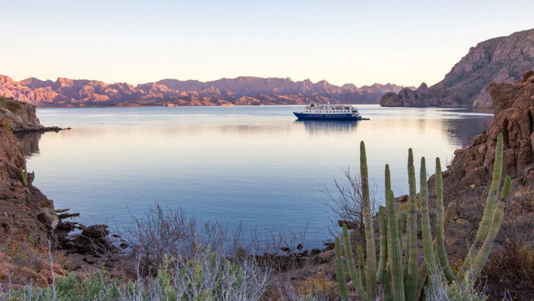 At a pastel sunset the Safari Voyager small ship anchors in a remote bay in Baja's Sea of Cortez surrounded by jagged mountains