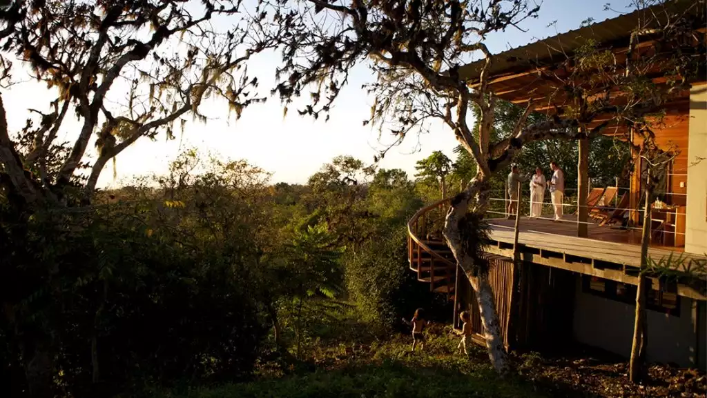 Nestled in the lush green highlands of the Galapagos, three guests stand on the patio of the Galapagos Safari camp lodge.