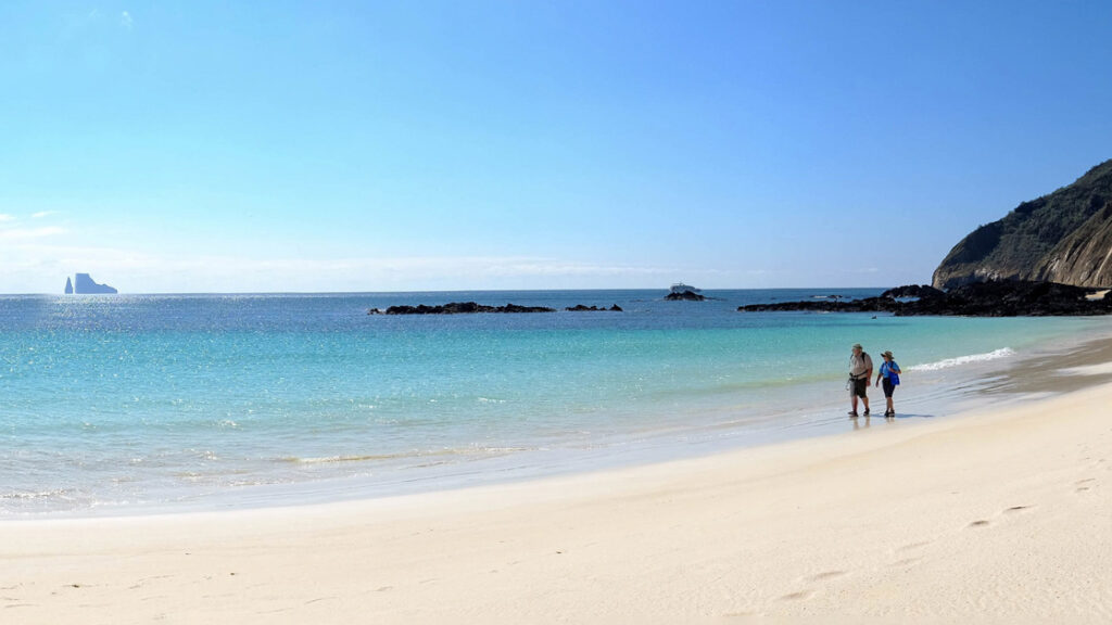 Couple walking along the wide open beach on a picturesque day in the Galapagos