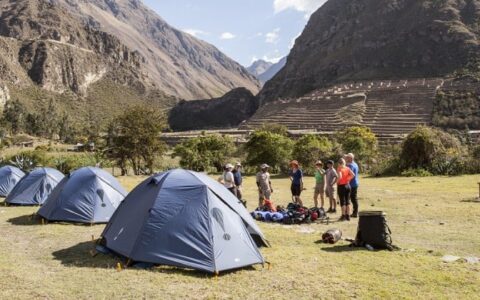 hikers set up tents at the bottom of incan ruins in peru