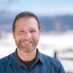 adventuresmith explorations director of sales and operations justin massoni stands smiling on a sunny day with snow in the background