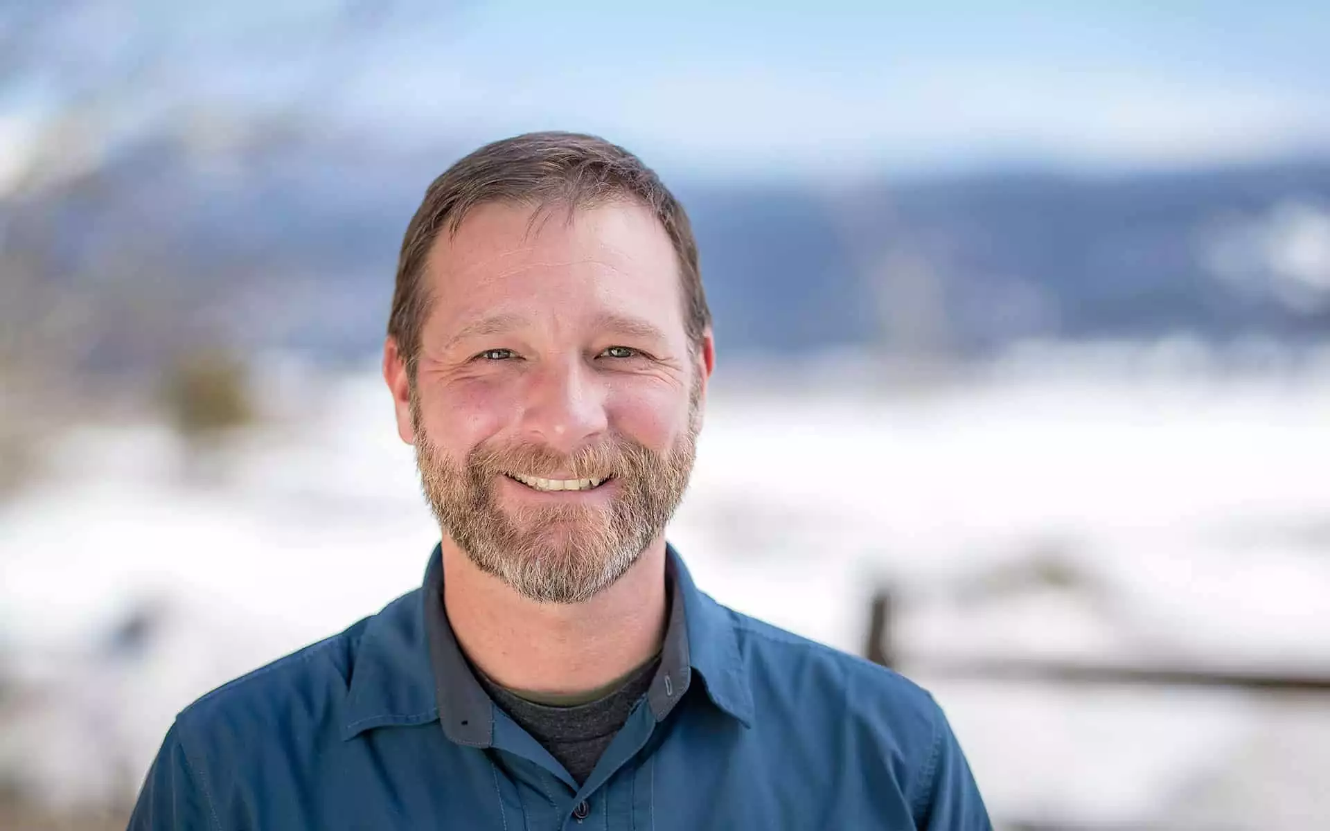adventuresmith explorations director of sales and operations justin massoni stands smiling on a sunny day with snow in the background