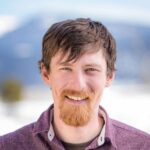 adventuresmith explorations adventure specialist kevin marshall stands smiling in front of a snowy mountainous backdrop