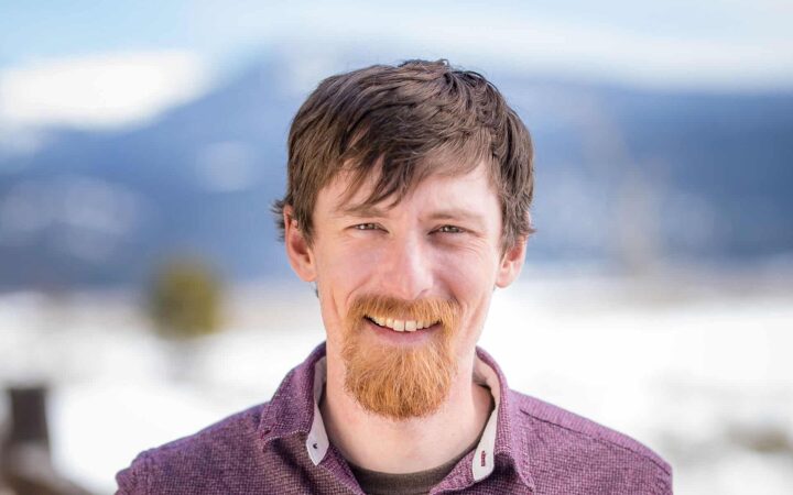 adventuresmith explorations adventure specialist kevin marshall stands smiling in front of a snowy mountainous backdrop