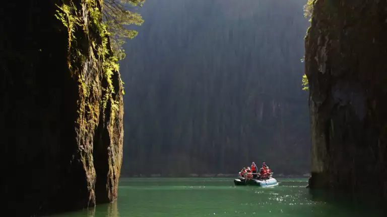 Zodic explring the narrow waterways of Alaska shown between 2 large landforms on a bright sunny day