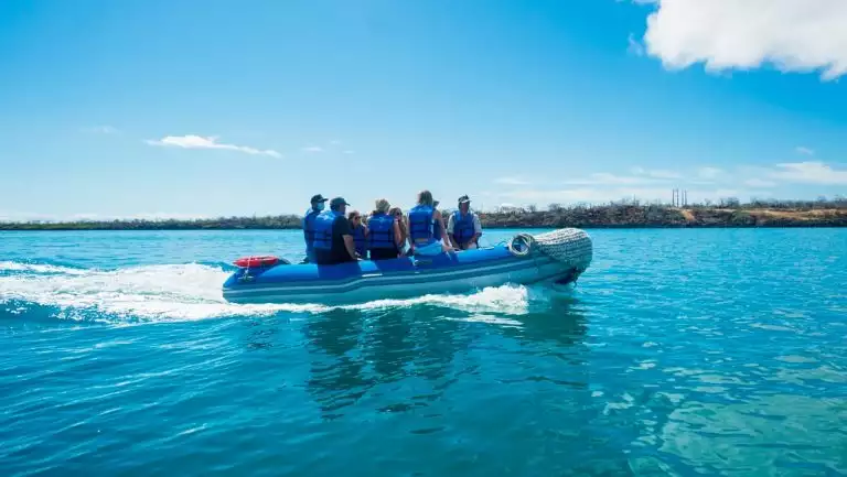 Galapagos travelers ride in a panga small boat under sunny skies en route to a shore excursion on an Ocean Spray cruise.