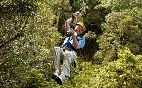 a traveler goes on a zip line with the jungle canopy below him on the panama adventure land tour