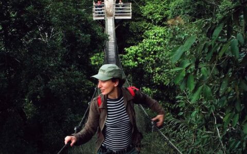 female solo traveler walking through the amazon jungle canopy on a land tour