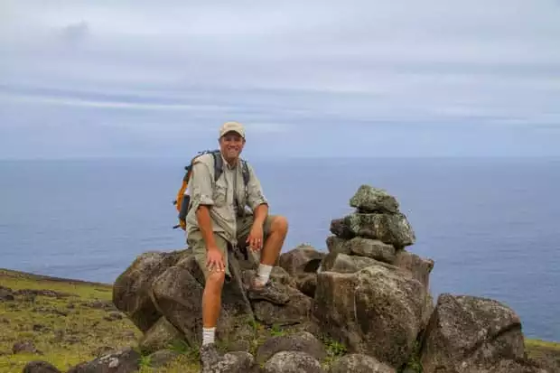 The author siting on rocks in front of the ocean smiling.