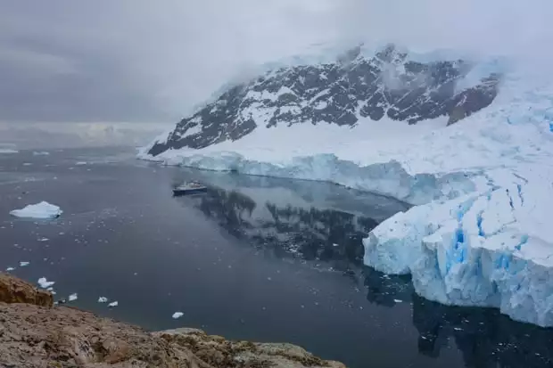 View from a hike of the ice shelf in Antarctica with small ship in the bay. 