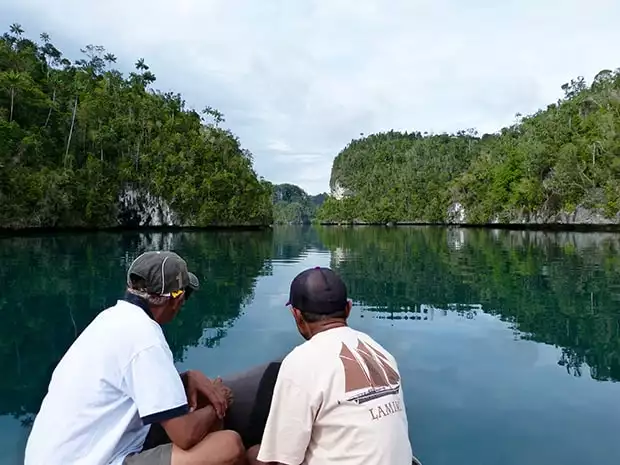 Local guides on a skiff leading the way through the islands on an excursion off a small ship cruise in Raja Ampat Indonesia. 