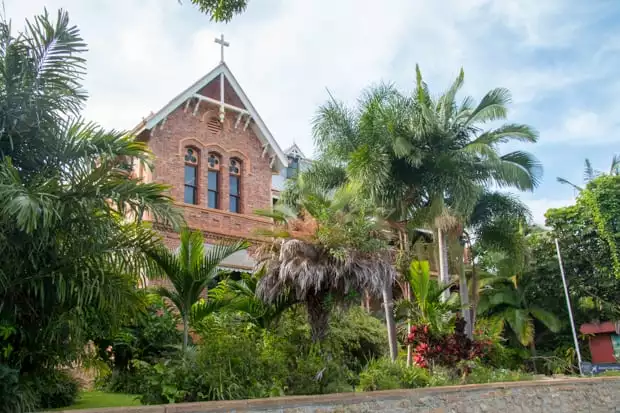 A church in Cooktown, Australia with palm trees in front.