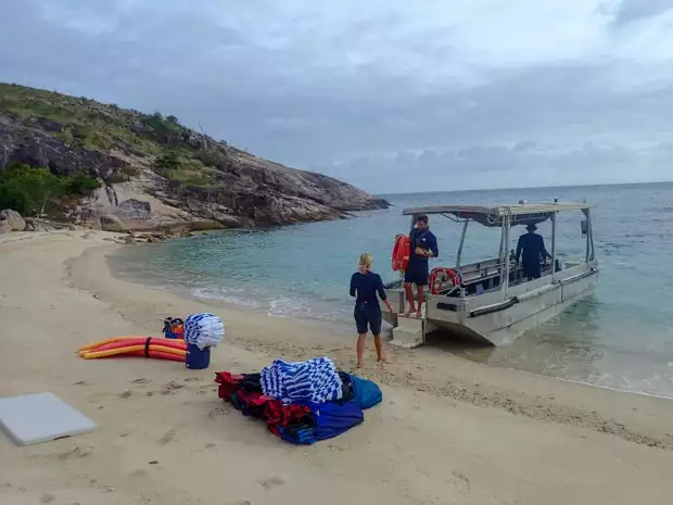 A metal tender dropping of supplies for a day at the beach for small ship cruisers with towels, swim noodles and a table.